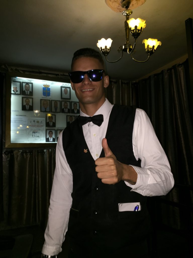 a man wearing sunglasses and a vest giving a thumbs up
