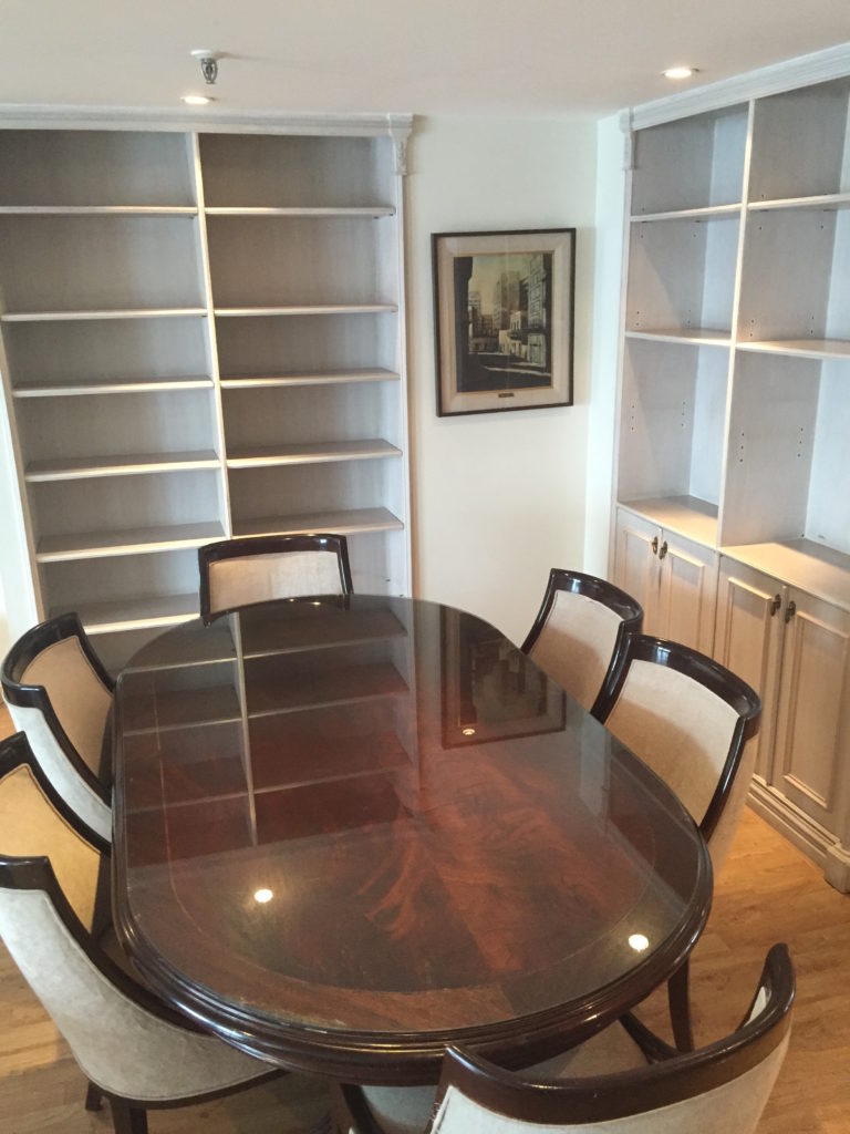 a table with chairs around it in a room with shelves
