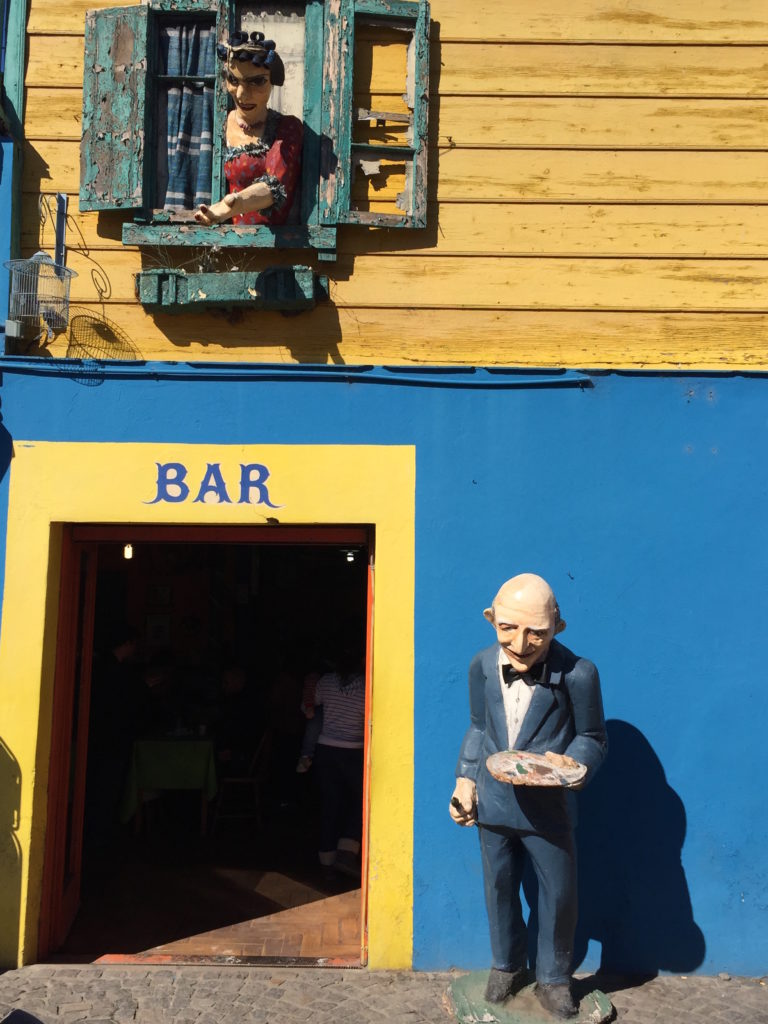 a statue of a man holding a plate in front of a bar