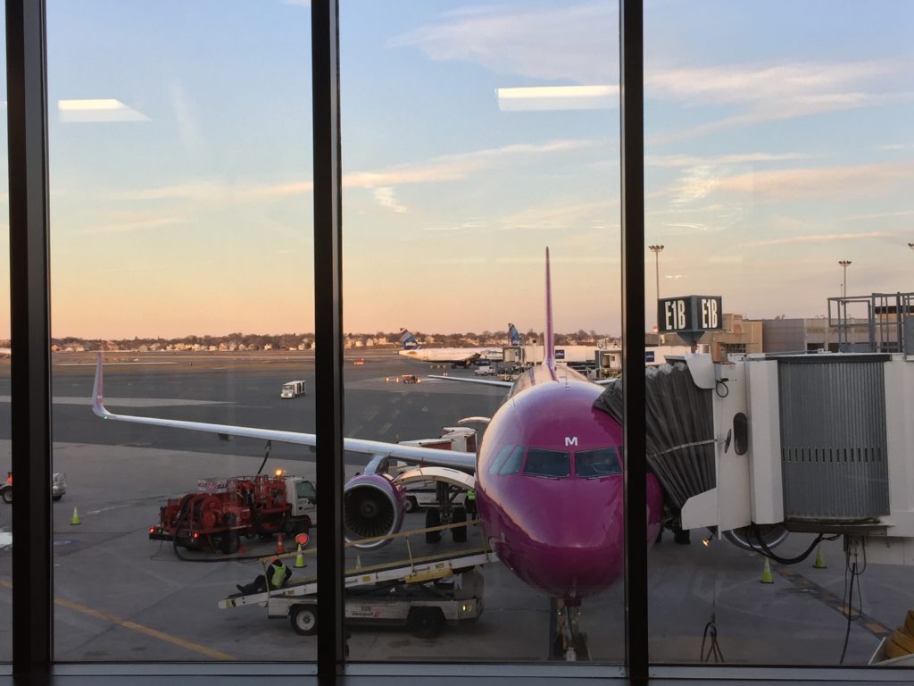 a window of an airport with a pink airplane