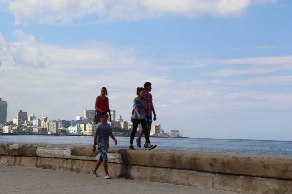 a group of people walking on a wall by water