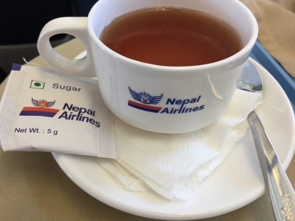 a cup of tea on a saucer with a packet of sugar
