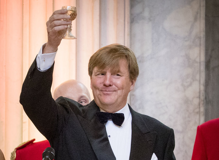 a man in a tuxedo holding up a wine glass