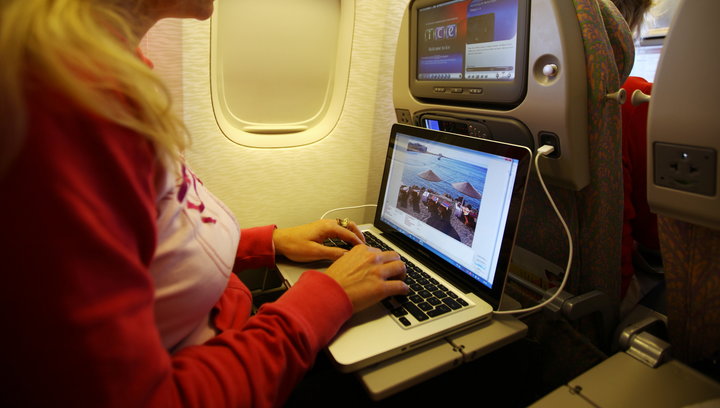 a woman using a laptop on an airplane