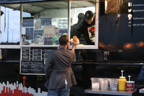 a man handing a sandwich to a man in a food truck