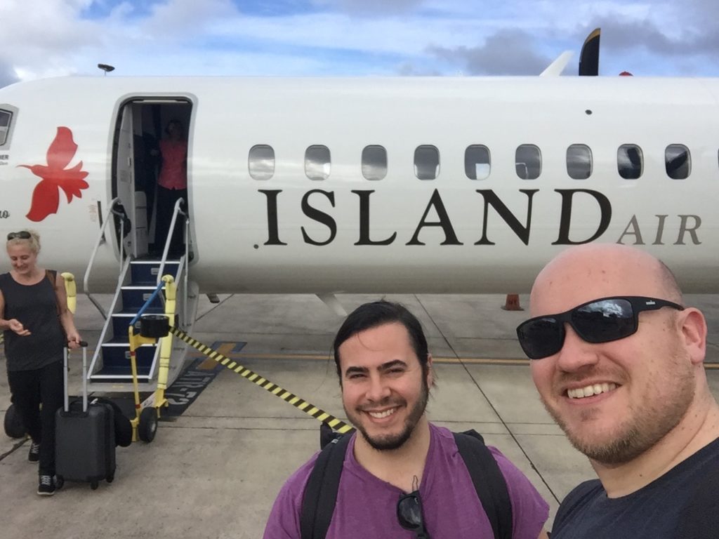 two men taking a selfie in front of an airplane