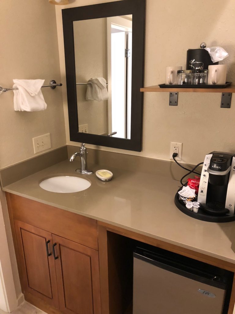 a bathroom sink with a mirror and a coffee maker