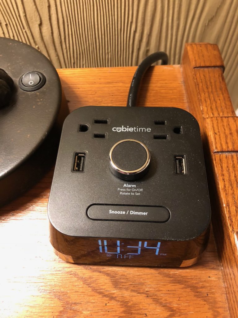 a black square alarm clock with a black cord