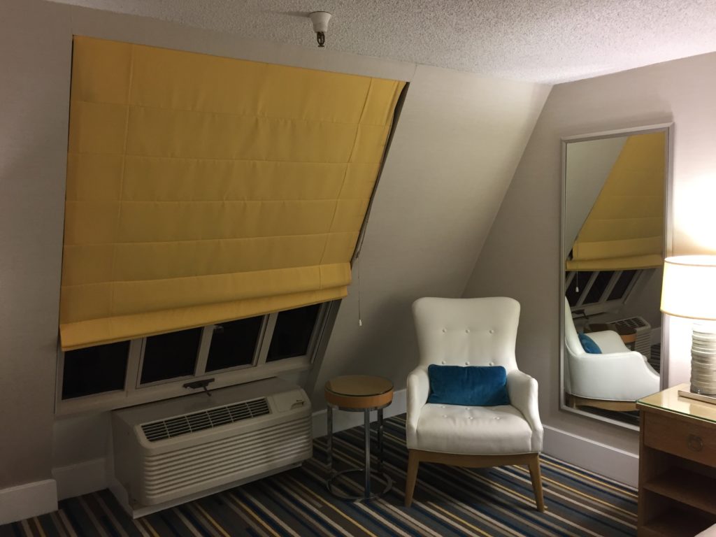 a room with a white chair and a yellow curtain