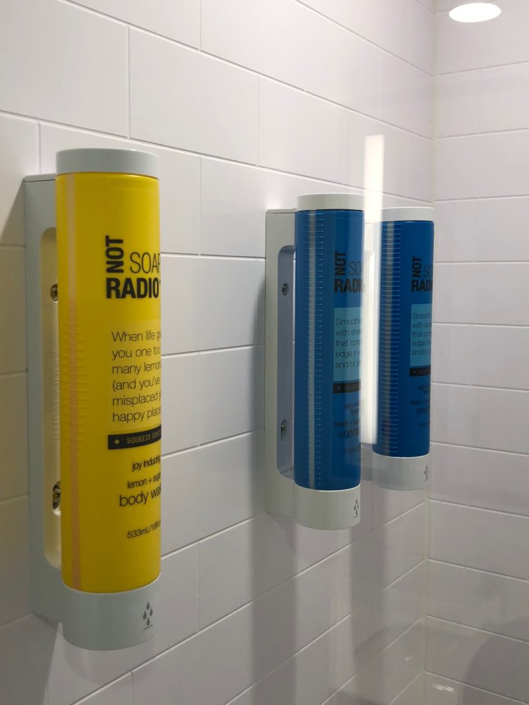 a yellow and blue soap dispensers on a white tile wall