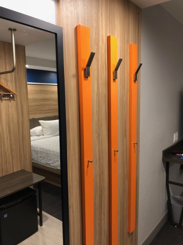 a room with a mirror and a row of orange hooks