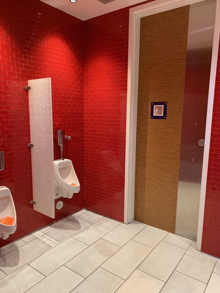 a bathroom with red tile walls and urinals