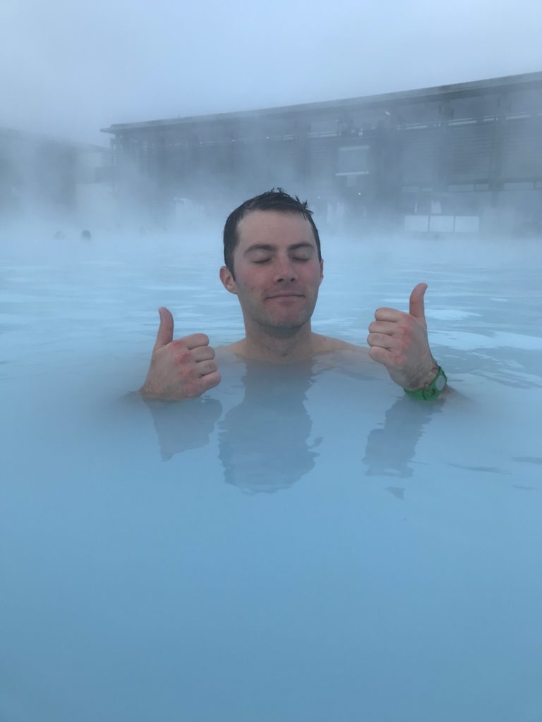 a man in a blue pool with two thumbs up