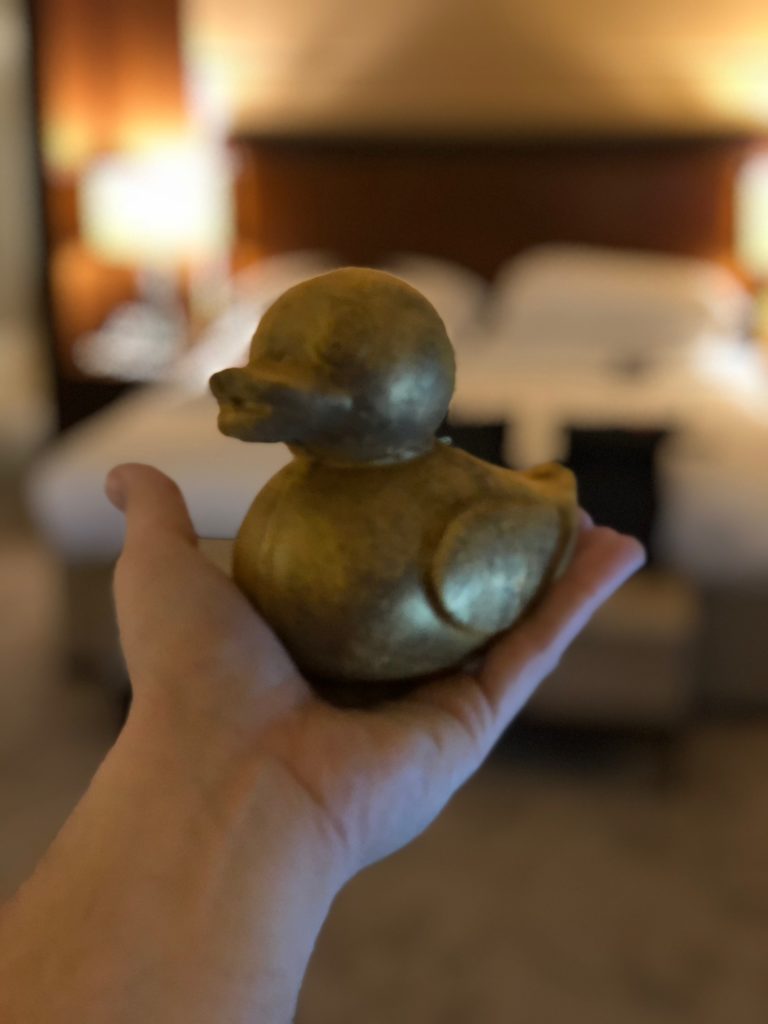 a hand holding a small gold duck