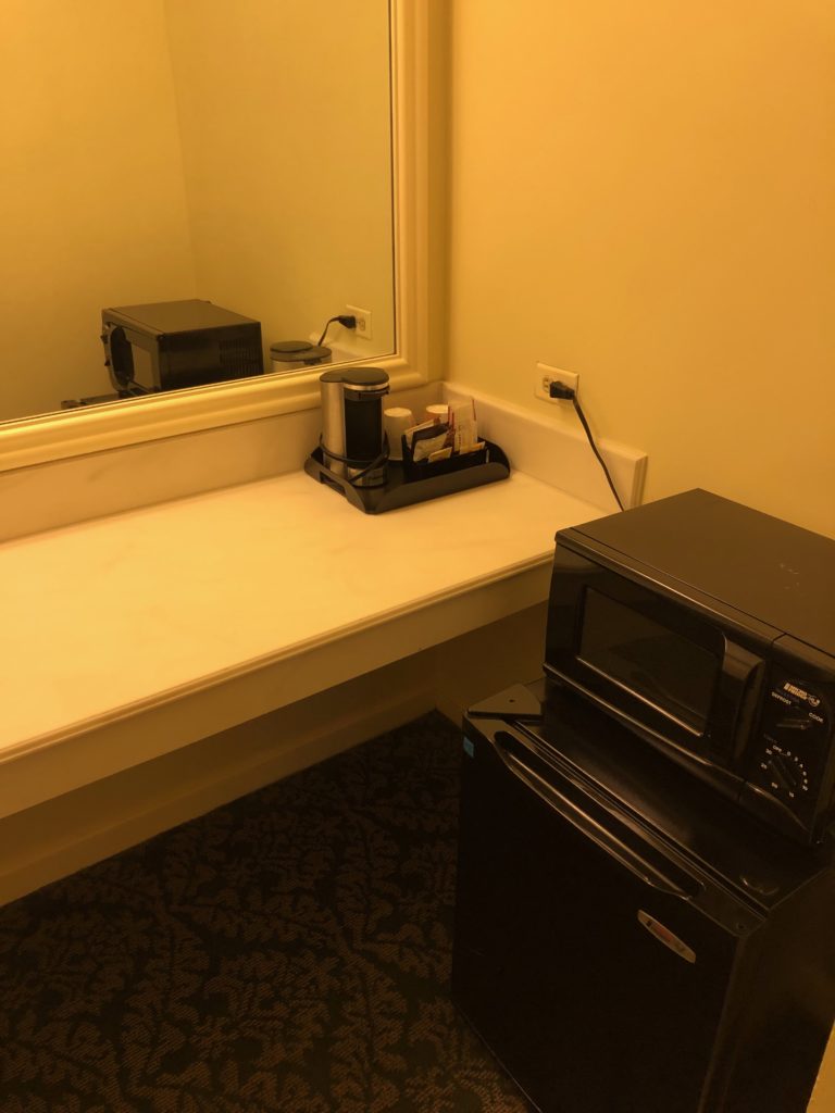 a black microwave on a counter next to a mirror