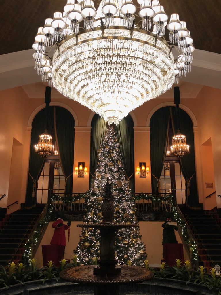 a large chandelier in a room with a christmas tree