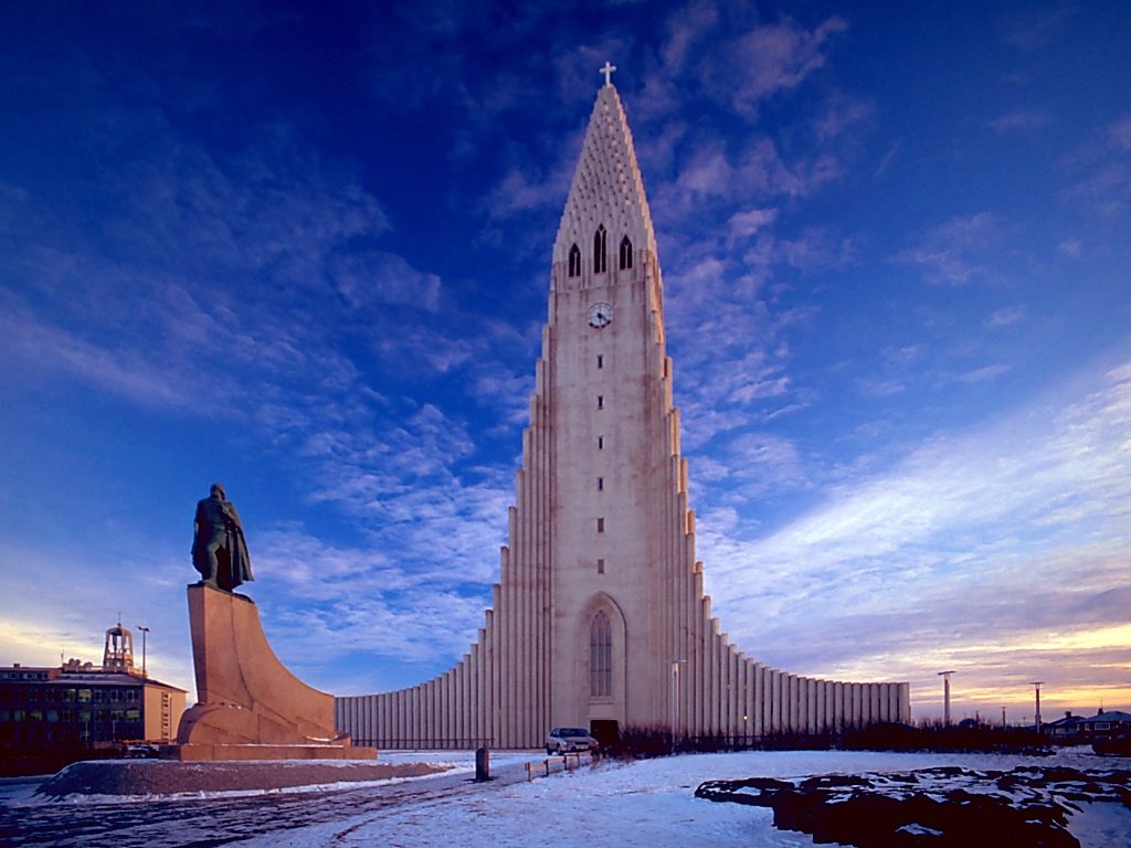 a tall building with a clock tower and a statue with Hallgrímskirkja in the background