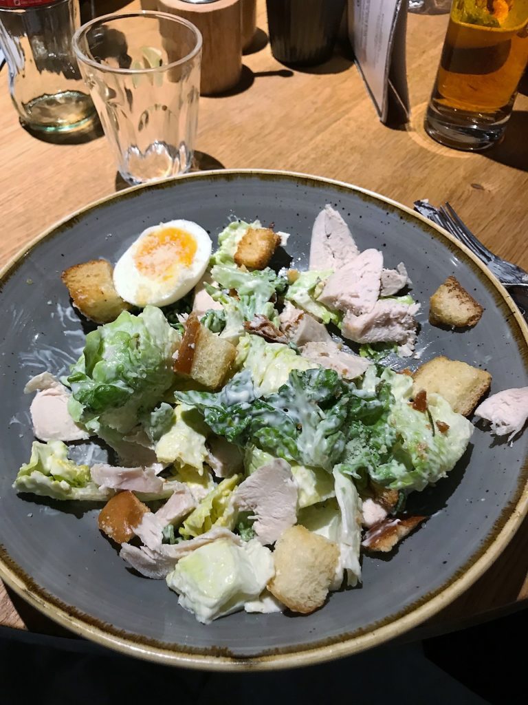 a plate of salad with chicken and croutons