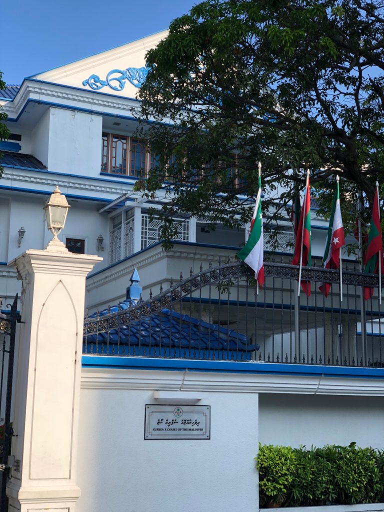 a white building with a fence and flags