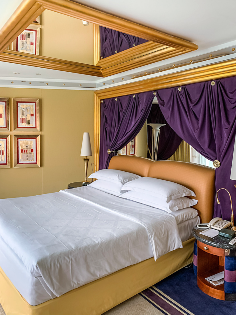 a bed with purple curtains and a gold frame