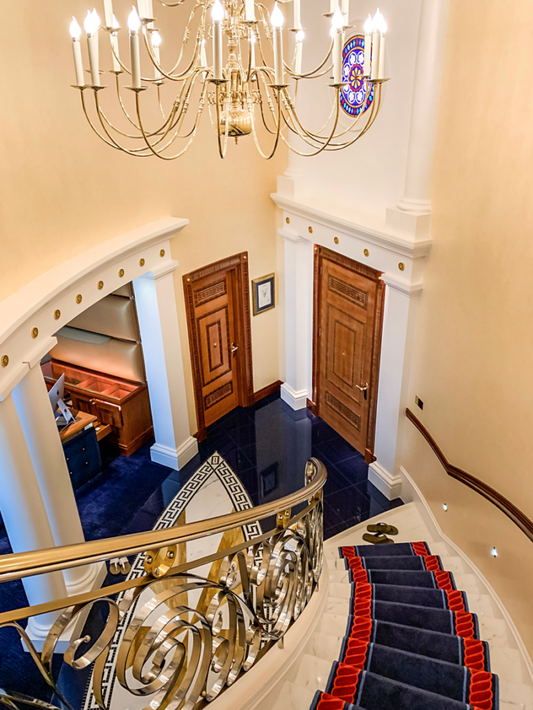 a staircase with blue carpet and chandelier