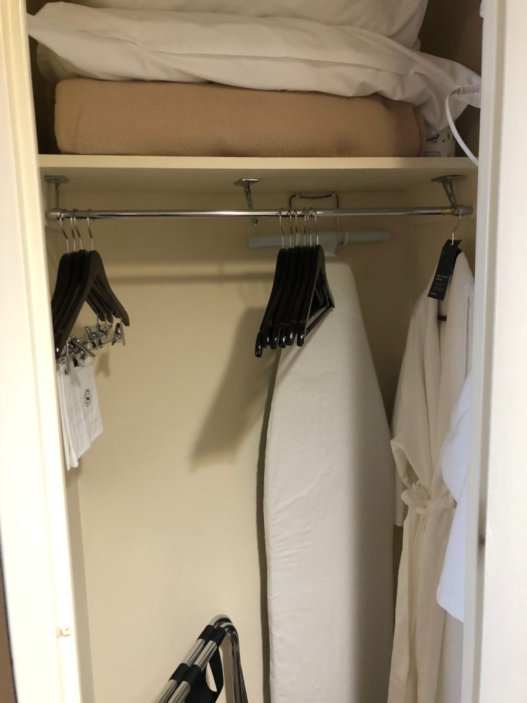 a closet with clothes and ironing board