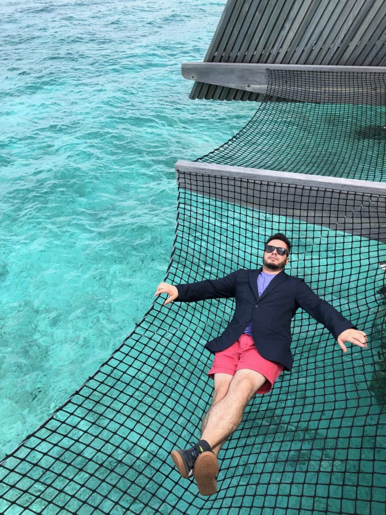 a man lying in a hammock over water