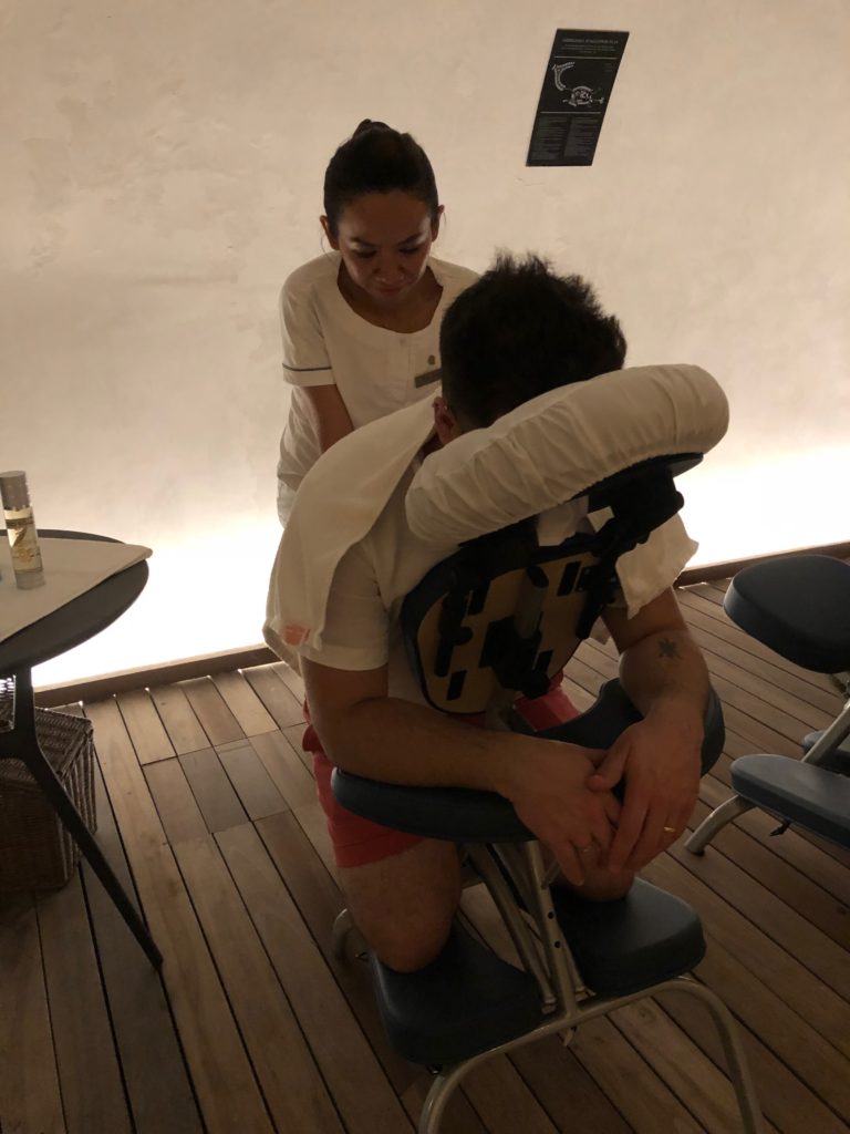 a man sitting in a massage chair with a woman in the background