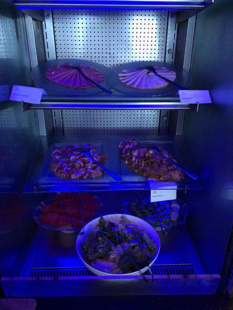 a display case with plates of food and a bowl of salad