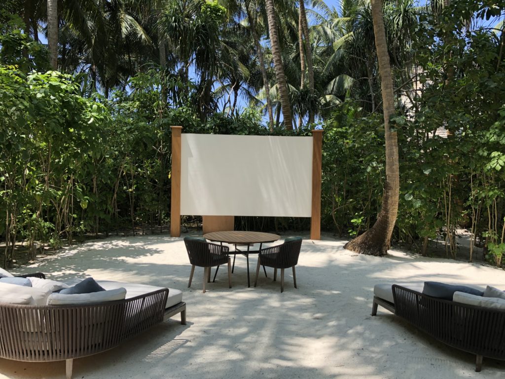 a table and chairs in a courtyard with trees in the background