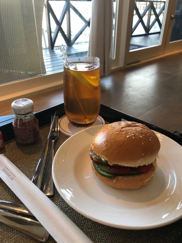 a burger on a plate next to a glass of tea