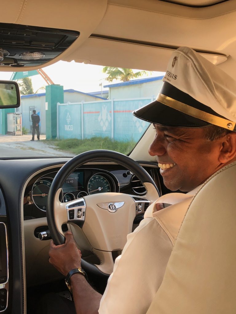 a man in a white hat and white jacket driving a car