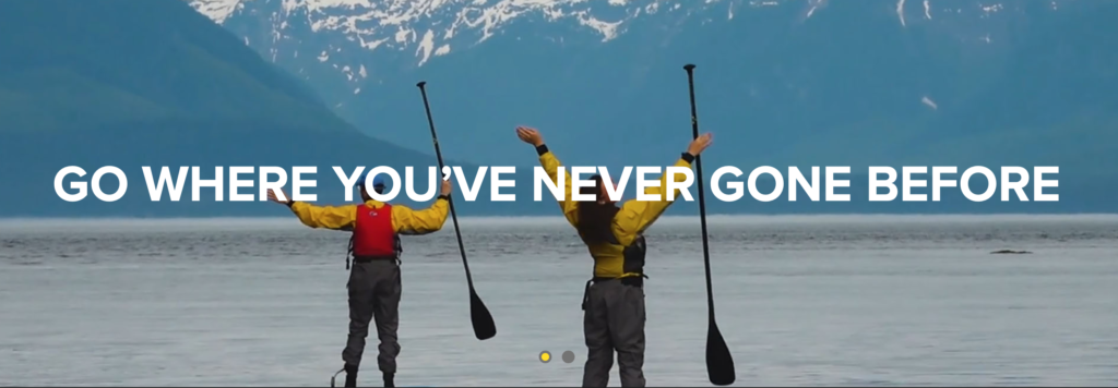 two people holding paddles in front of a mountain