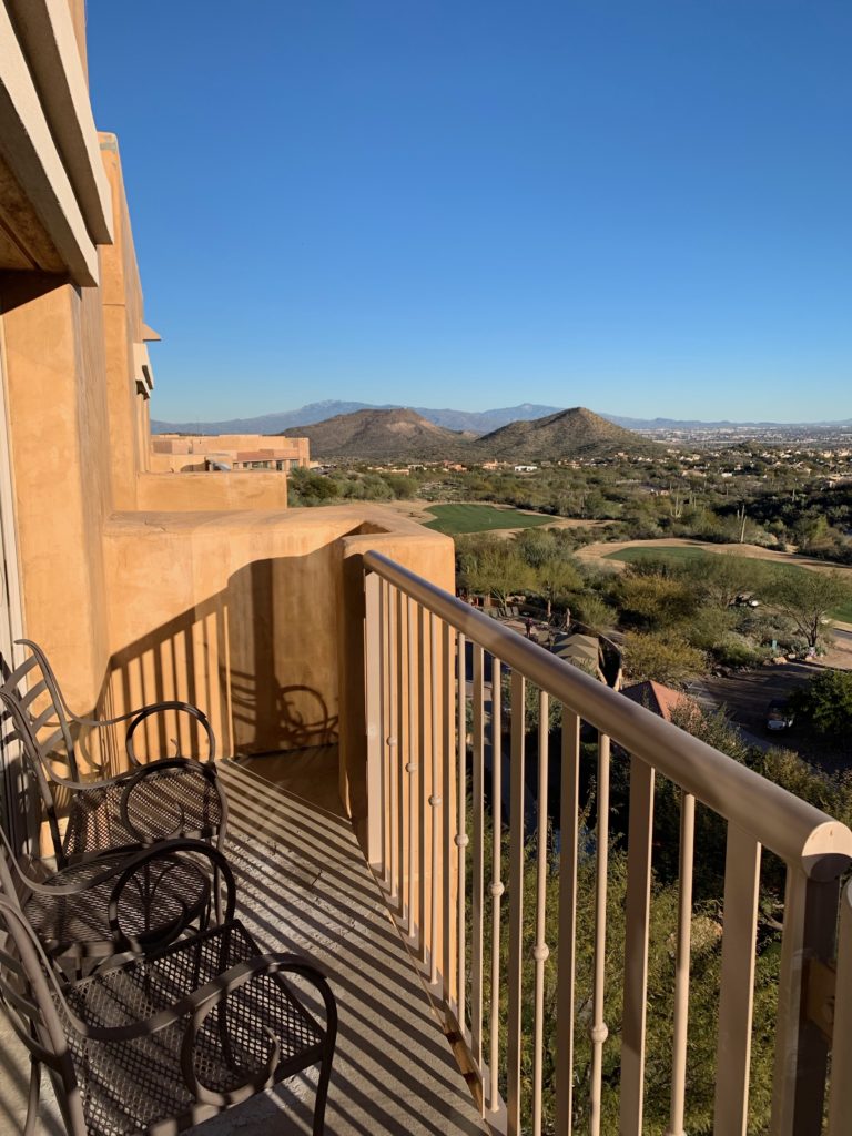 a balcony with chairs and a view of a city