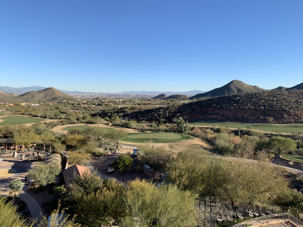 a golf course with trees and mountains in the background