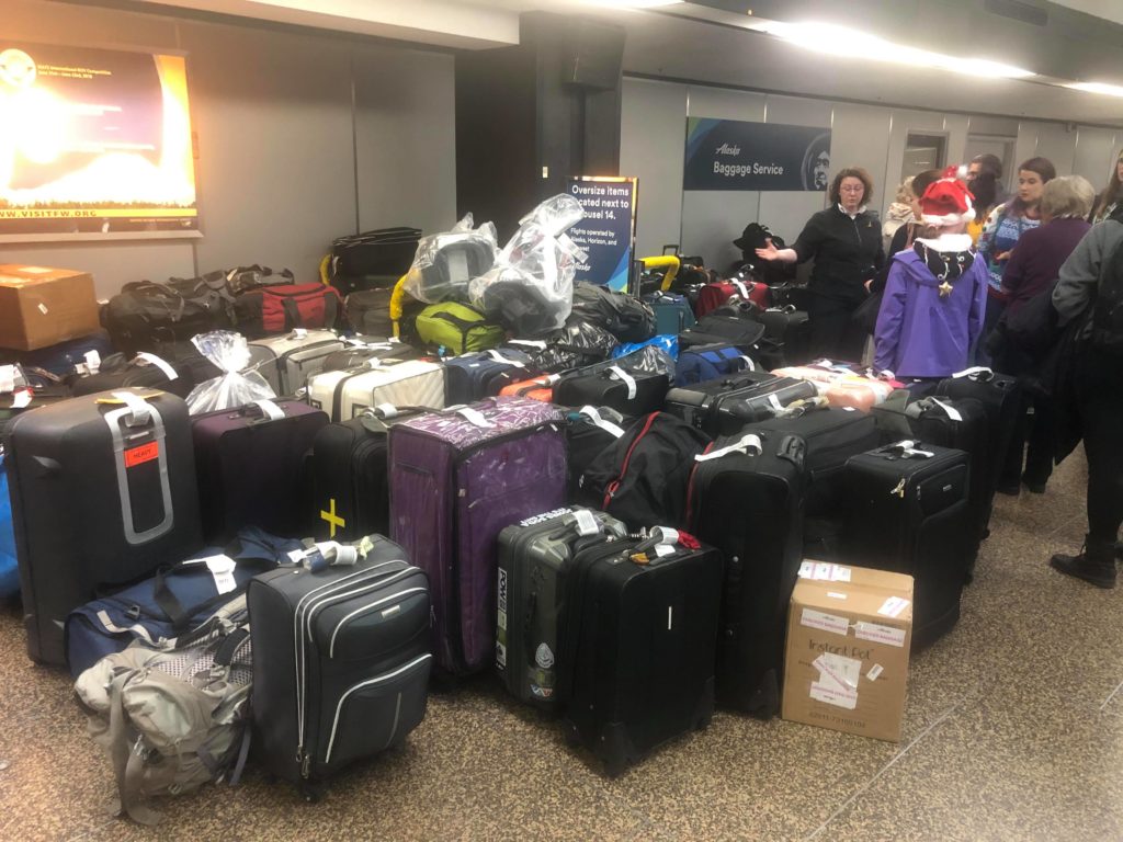 a group of people standing next to a large group of luggage