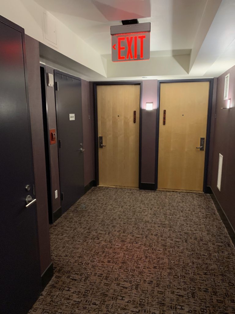a hallway with doors and a red sign