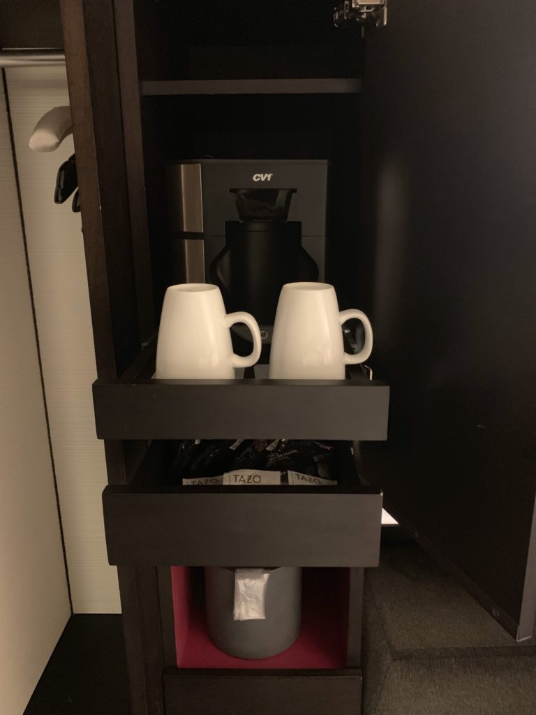 a coffee machine and two white mugs in a drawer