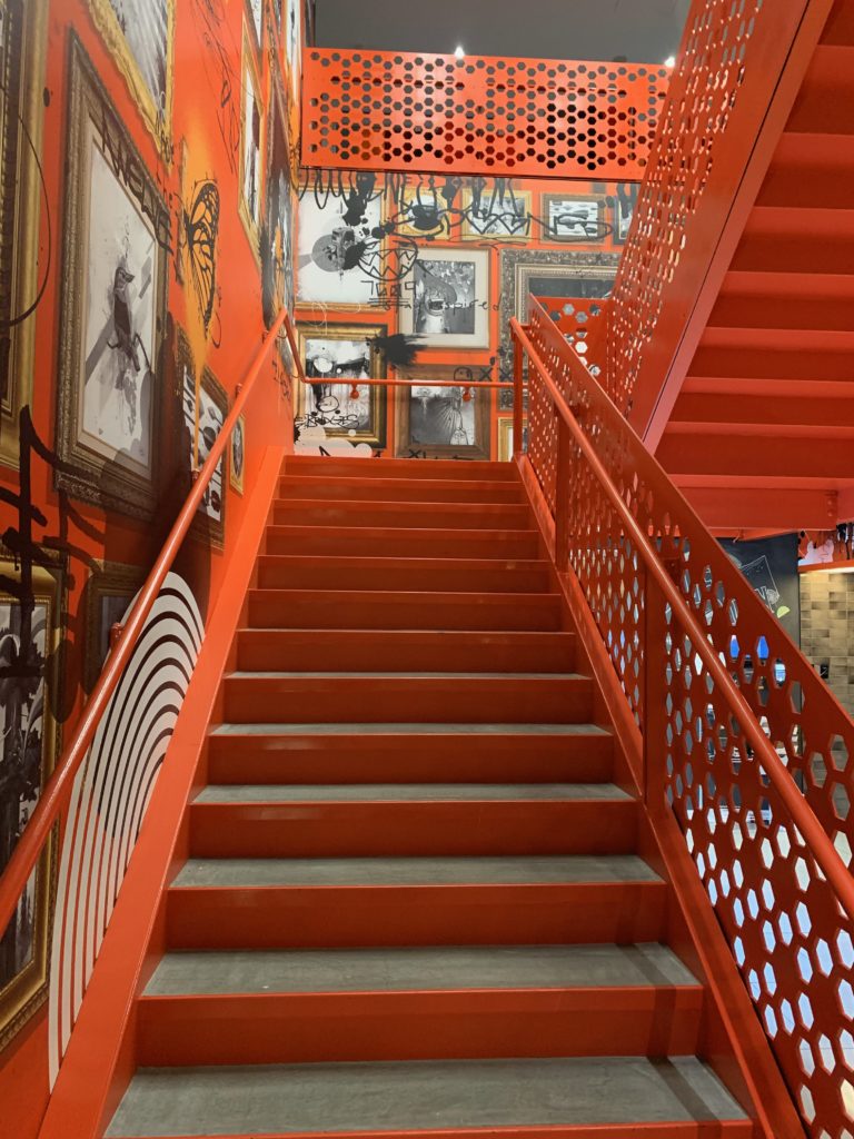 a orange staircase with art on the wall