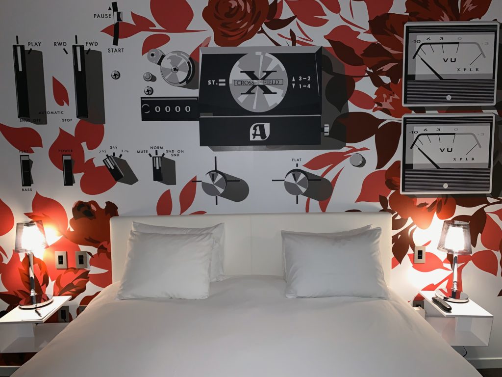 a bed with a white bed and a wall with a picture of radio and speakers