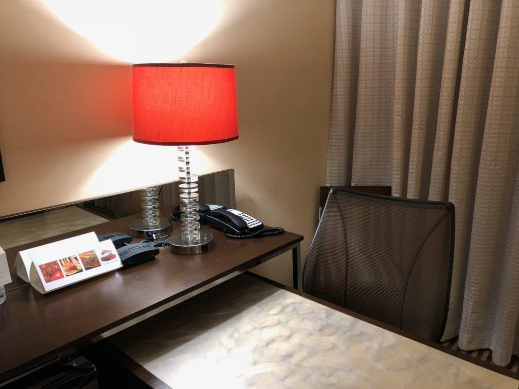 a desk with a lamp and a phone on it