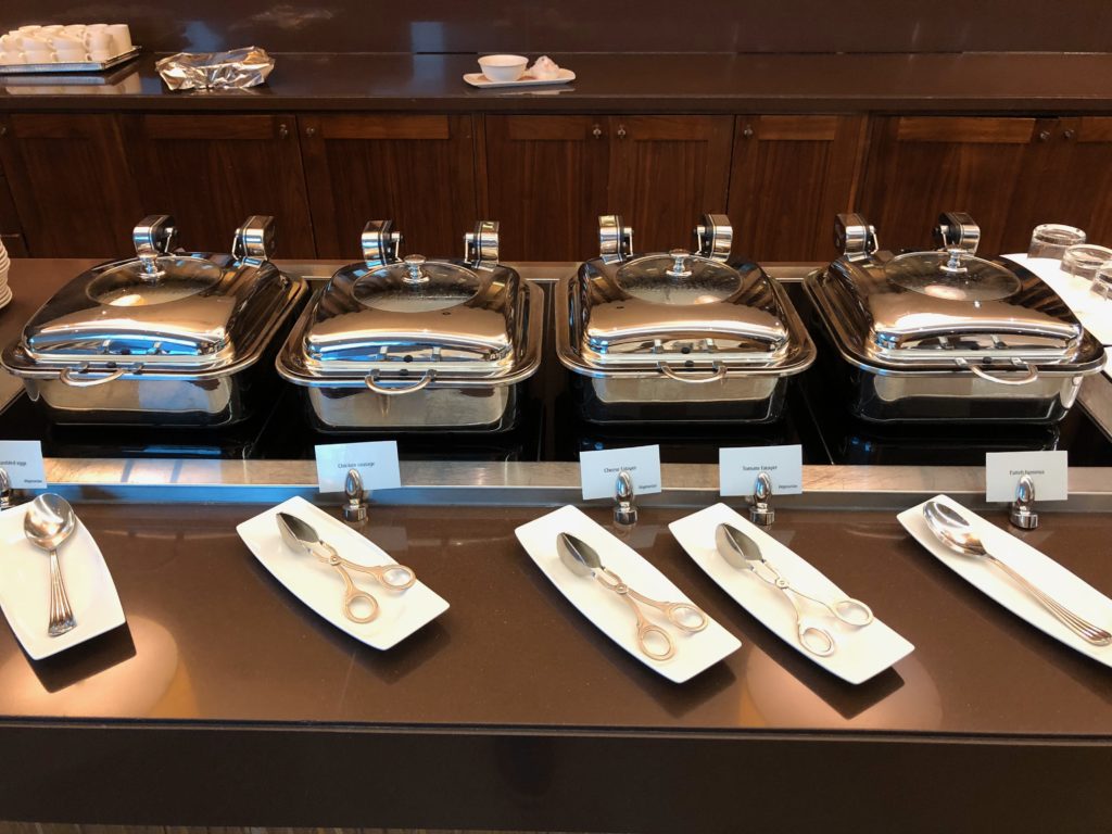 a row of silver containers with lids and spoons on a counter