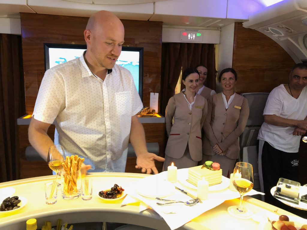 a man standing in a room with a table with food and people in the background