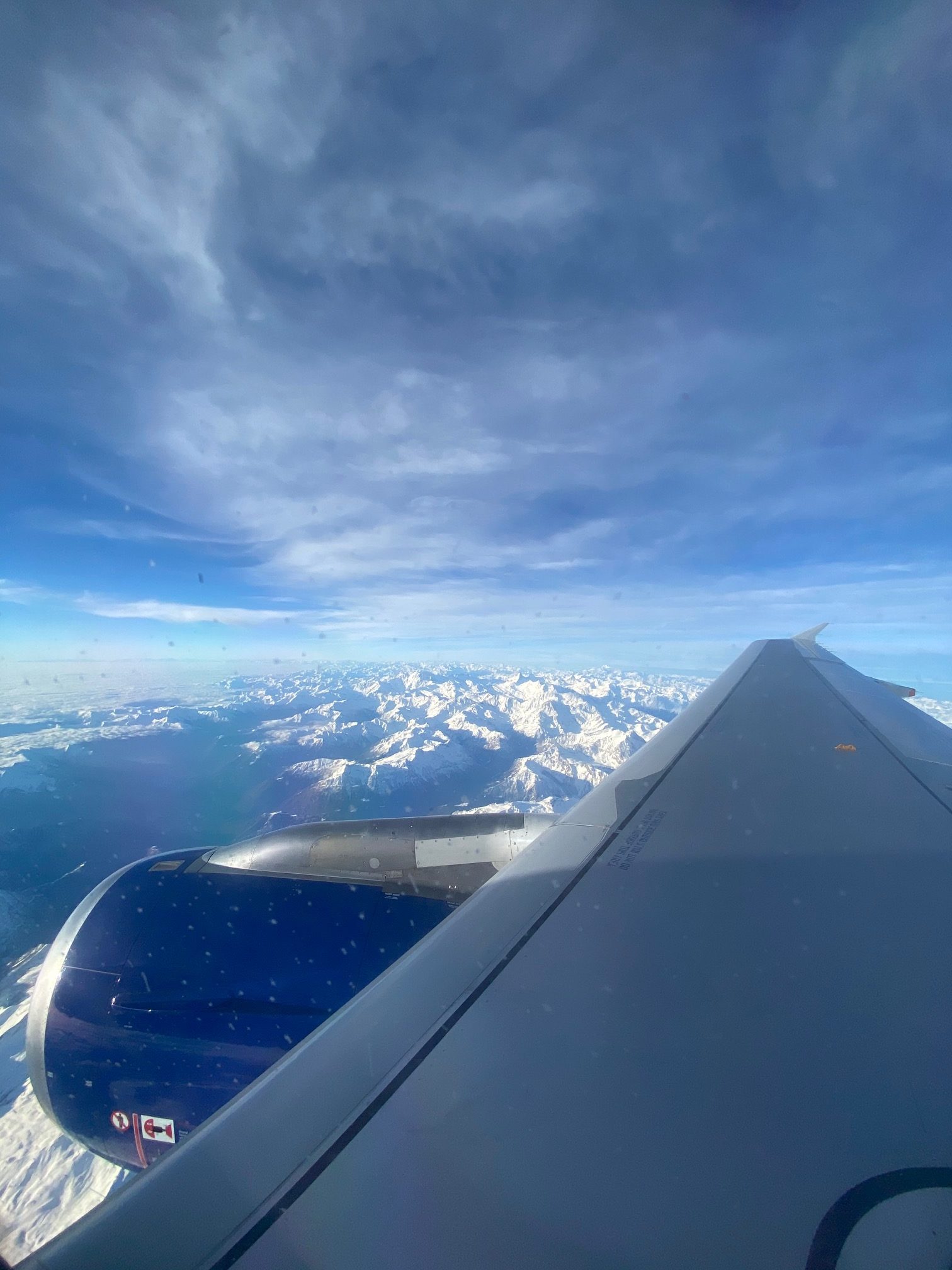 an airplane wing and snow covered mountains