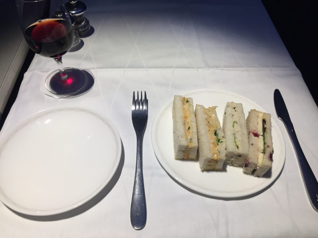 a plate of sandwiches and a glass of wine