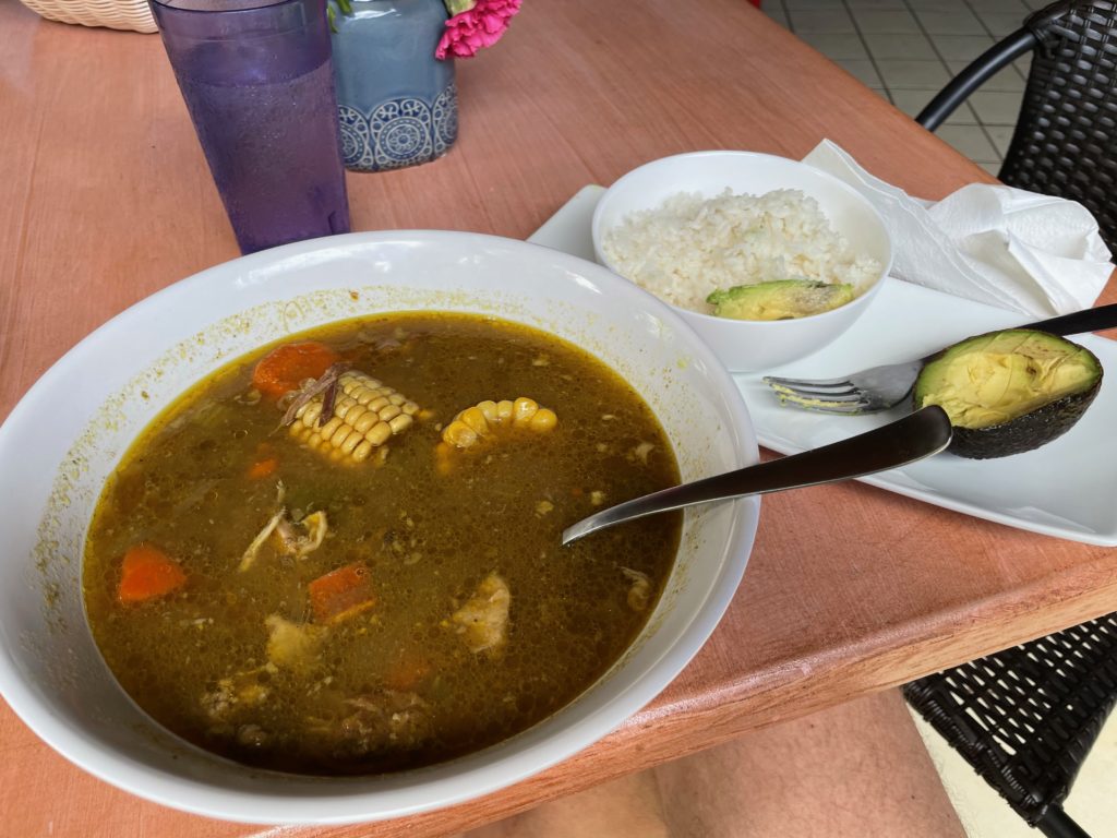 a bowl of soup with vegetables and rice on a table