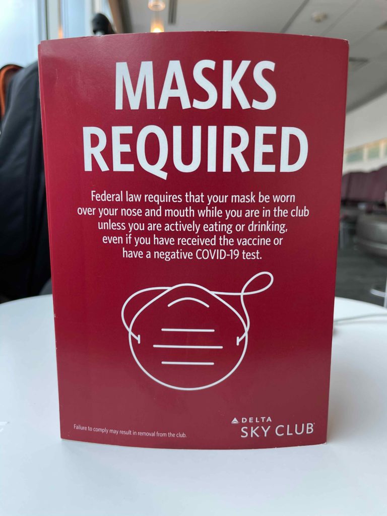 a red sign with white text and a face mask on it