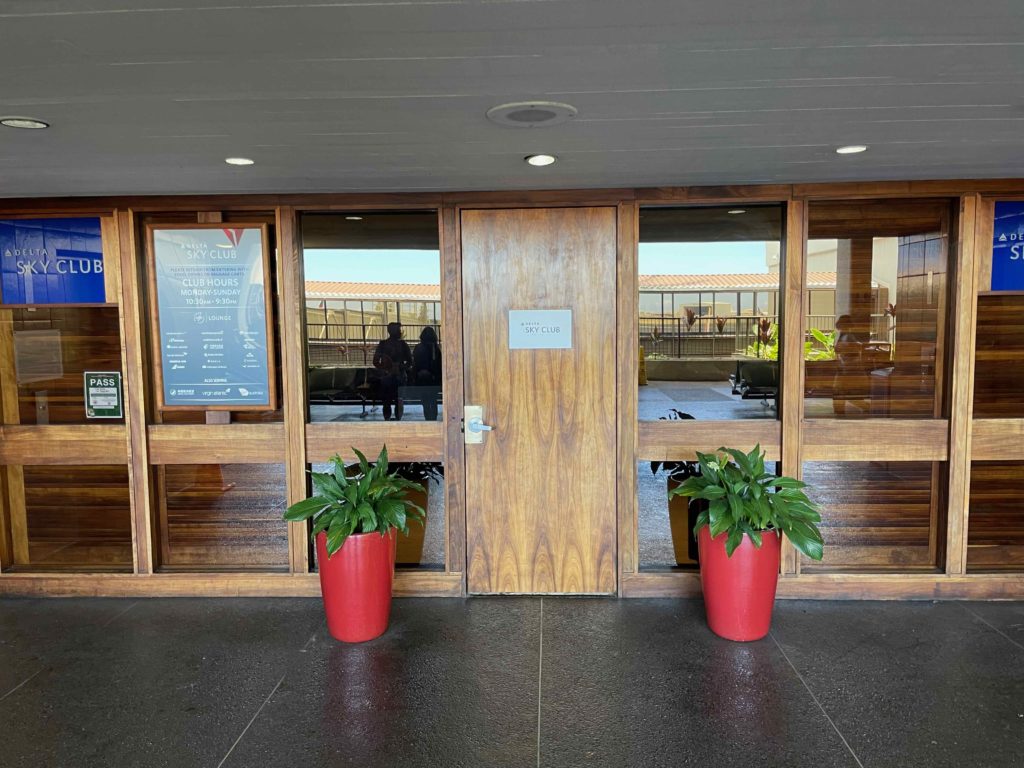 a wooden door with glass windows and plants in front of it