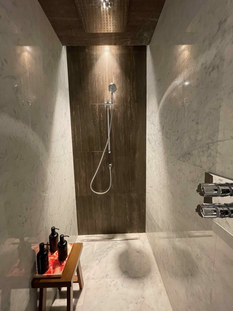a shower with a shower head and a tile wall