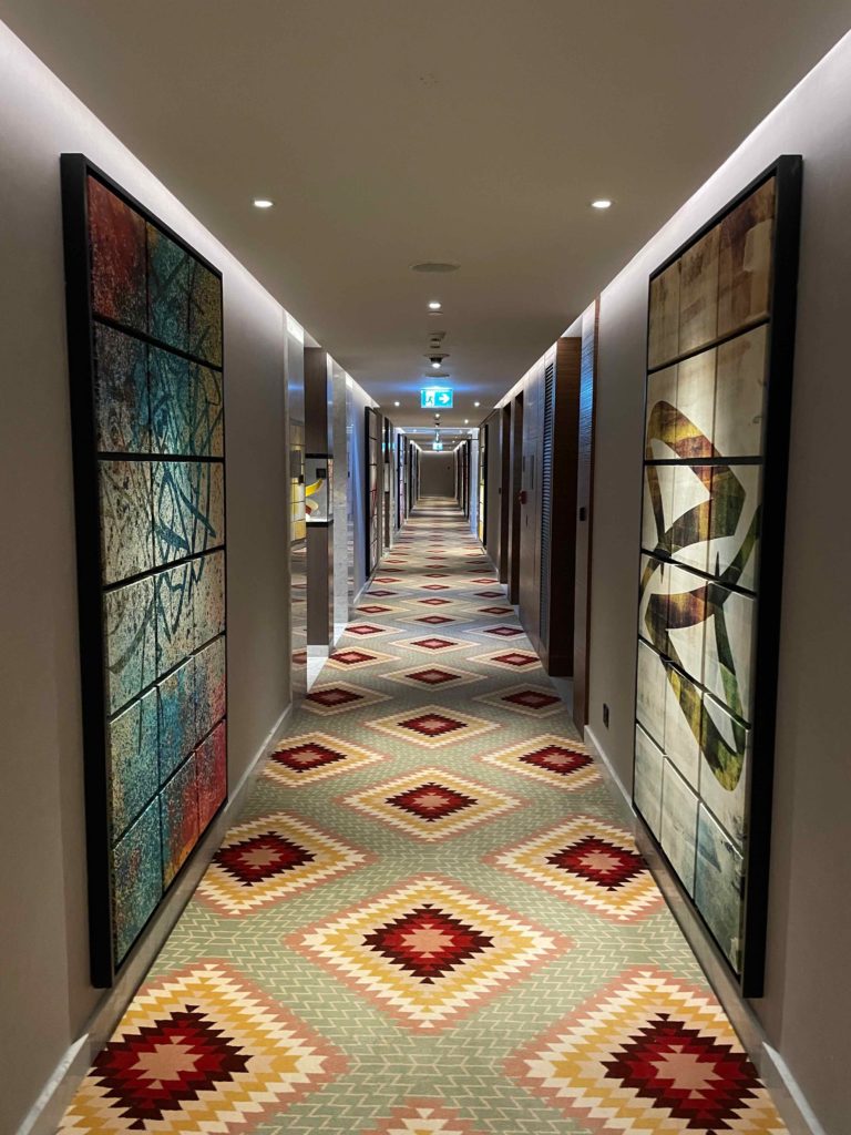a long hallway with colorful carpet and art on the walls